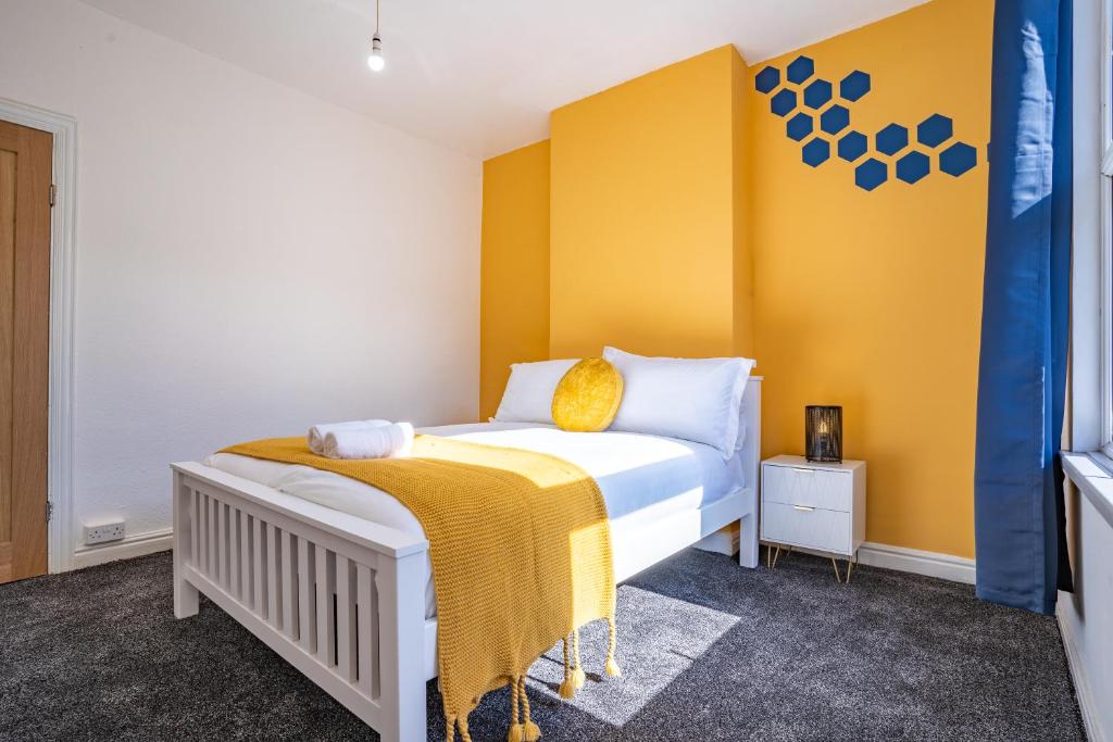 a bedroom with a bed with a yellow wall at STAYZED E - NG7 Free WiFi, Parking, Stylish House Near City Centre - Great For Tourists, Families, Contractors & Long Stays in Nottingham