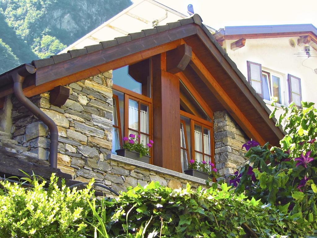 ein Steinhaus mit Fenstern und Blumen darauf in der Unterkunft Studio La Stalla in Aurigeno