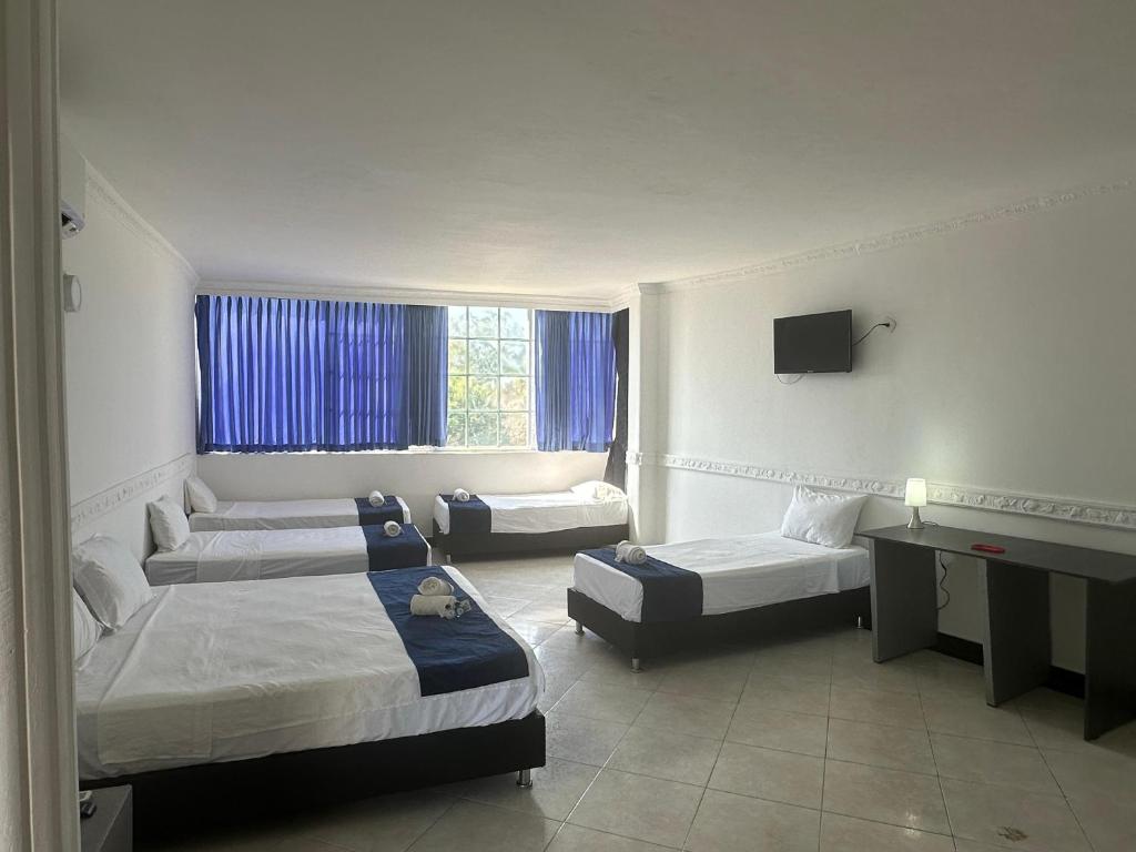 a hotel room with three beds and a television at SGH Castillo Aqua in Santa Marta