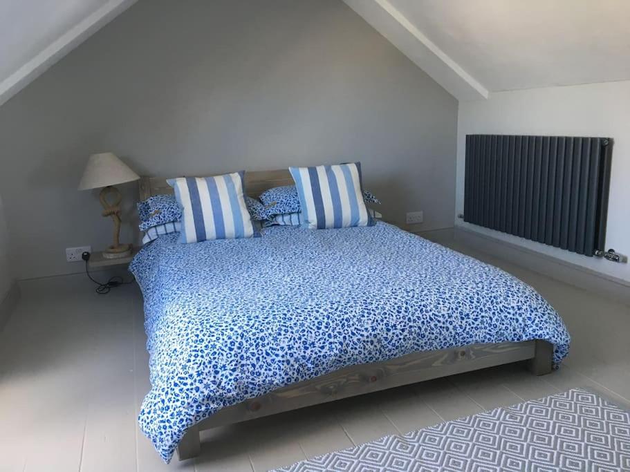 1 dormitorio con 1 cama grande con almohadas azules en Sea Breeze - 3 Bed House, Parking for 2 Cars, en St Ives