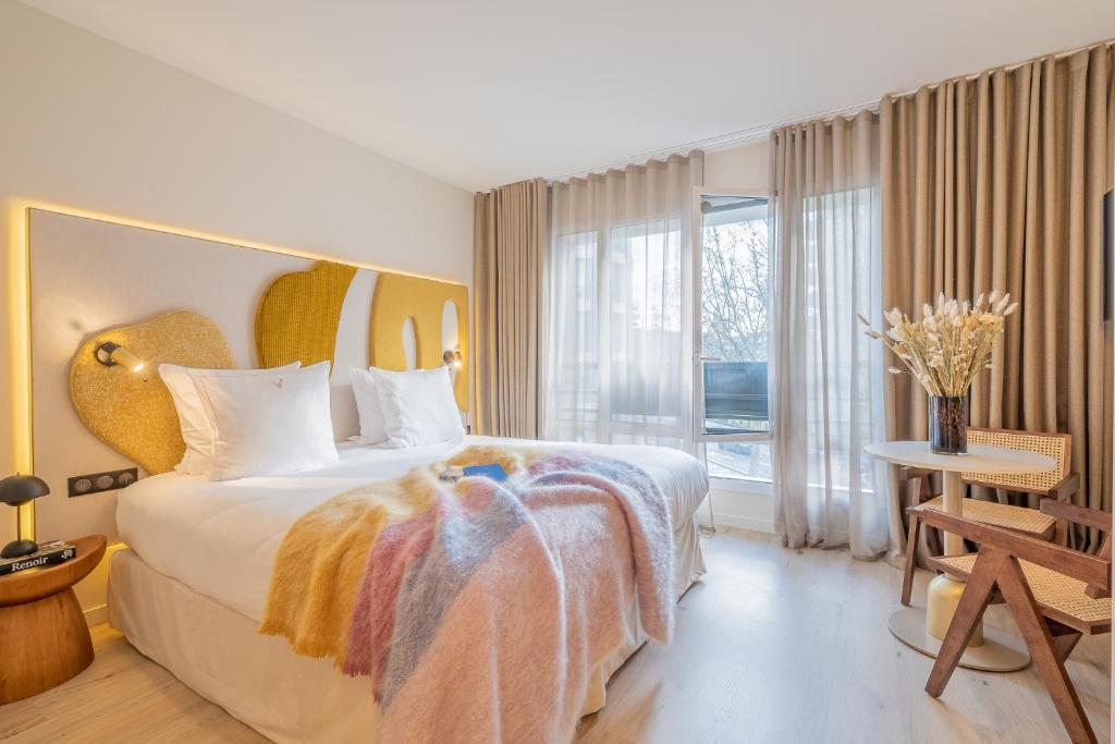 a bedroom with a large bed with a large window at Yuna Porte-Maillot - ApartHotel in Paris