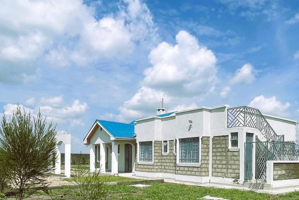 una pequeña casa blanca con techo azul en Riri Country Living Isinya, en Kitengela 