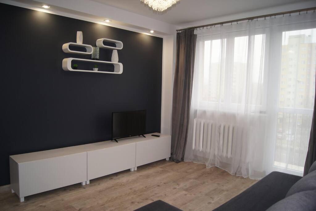 a living room with a flat screen tv on a black wall at Mieszkanie osiedle Północ in Koszalin