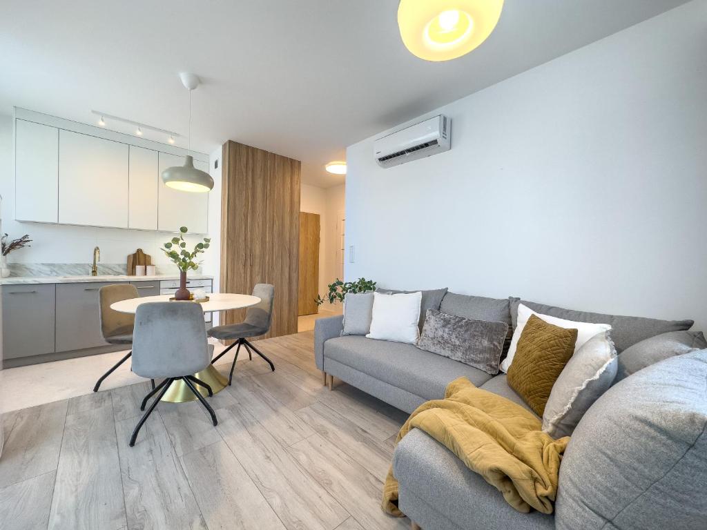 uma sala de estar com um sofá, uma mesa e uma cozinha em Krakowska Oaza Komfortu - Apartament Premium z Garażem em Cracóvia