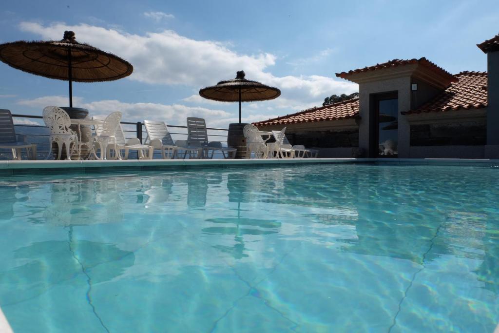 una gran piscina con sillas y sombrillas en Quinta da Bandeira - Casa de Férias no Douro, en Mártir