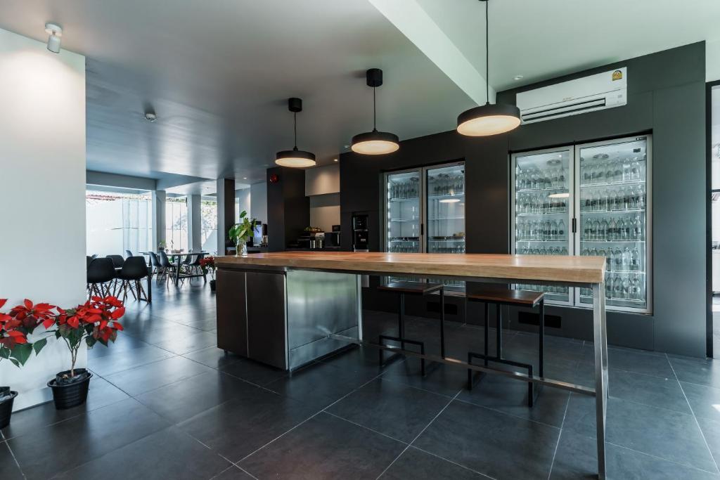 A modern common area has a long communal table beside a drinks refrigerator.