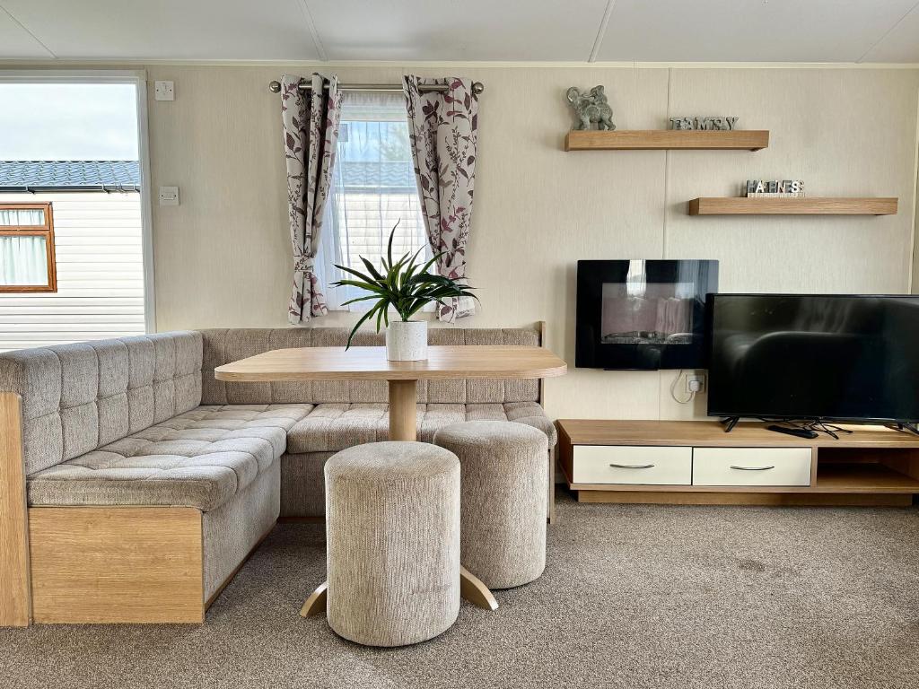 a living room with a couch and a table and a tv at Haven Seashore Holiday Park in Caister-on-Sea