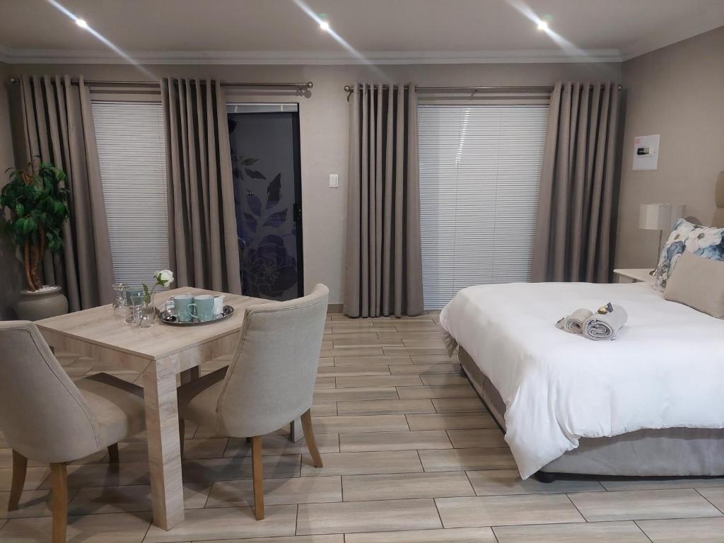 um quarto com uma cama, uma mesa e cadeiras em Bella Rosa em Potchefstroom