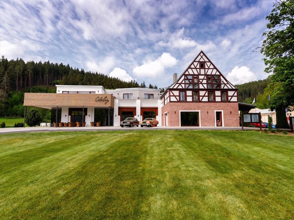 uma casa grande com um campo relvado em frente em Cihelny Golf & Wellness Resort em Karlovy Vary