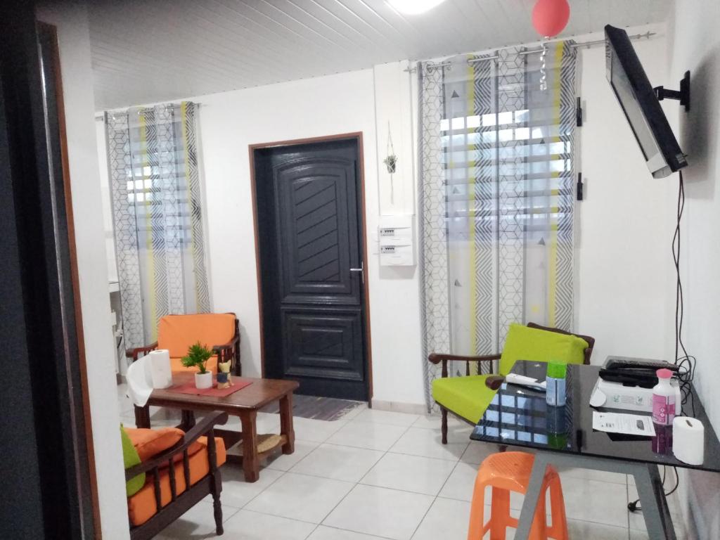 a living room with two chairs and a door at Un T2 climatisé, une nuit in Kourou