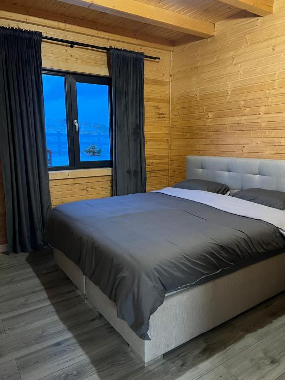 een slaapkamer met een groot bed in een houten muur bij Cabana Stil A in Mărişel