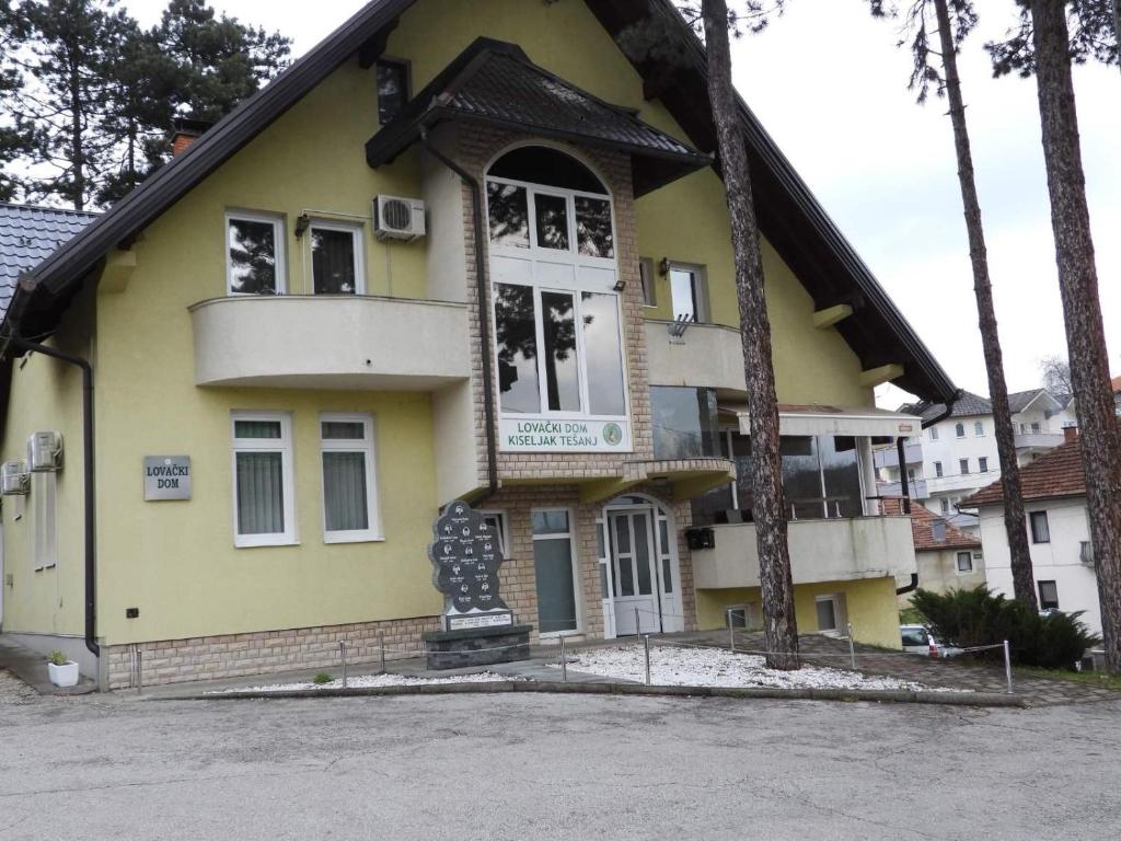 Una casa amarilla con un árbol delante. en Restoran&Motel and apartmants Lovacka prica, en Tešanj