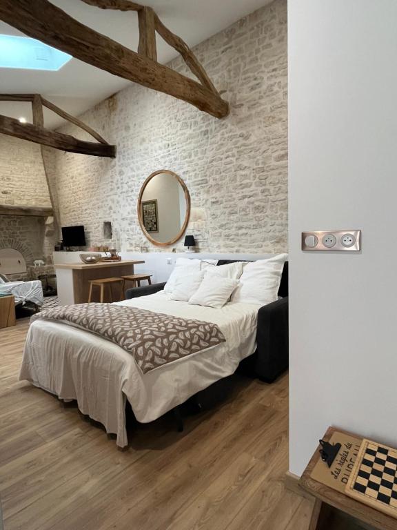 une chambre avec un grand lit et un mur en pierre dans l'établissement Chez Bibou, à Anais