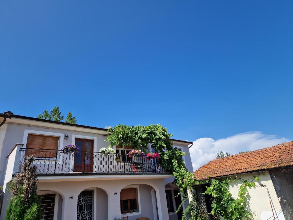 ein weißes Haus mit einem Balkon mit Blumen darauf in der Unterkunft Wine House in Capannori
