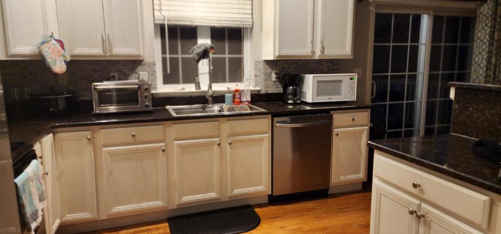 eine Küche mit weißen Schränken, einer Spüle und einer Mikrowelle in der Unterkunft Cozy Home away from Home in Westbrookville