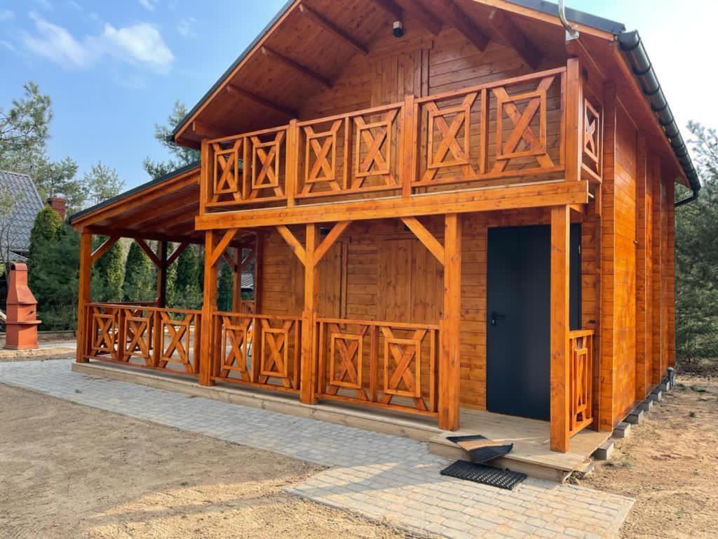 een grote houten hut met een grote deur bij Domek na Barcowej in Ostrowo