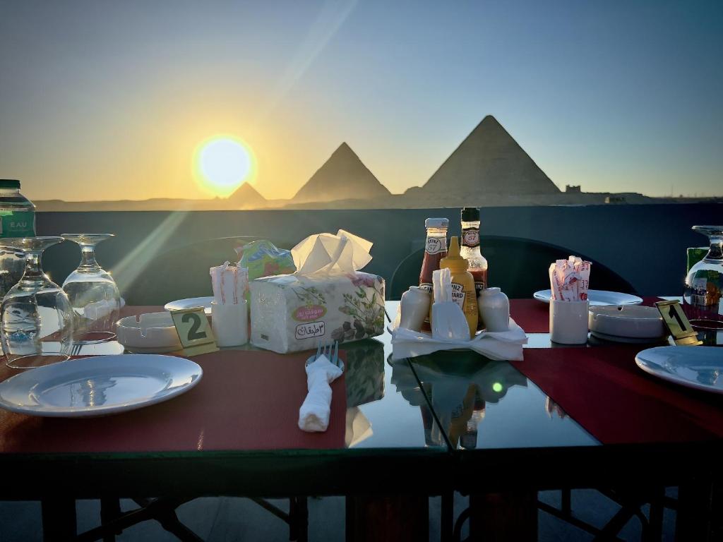 uma mesa com vista para as pirâmides e o pôr-do-sol em Pyramids Hotel no Cairo