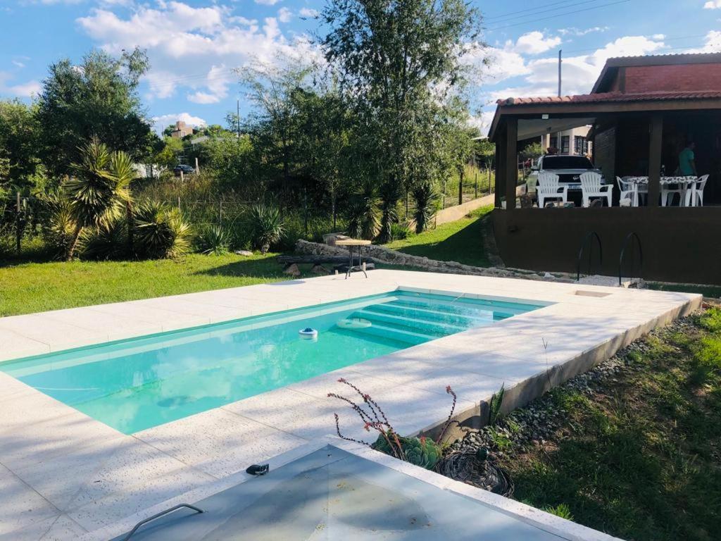 een zwembad in een tuin met een huis bij Casa amplia con pileta in Villa Parque Siquiman