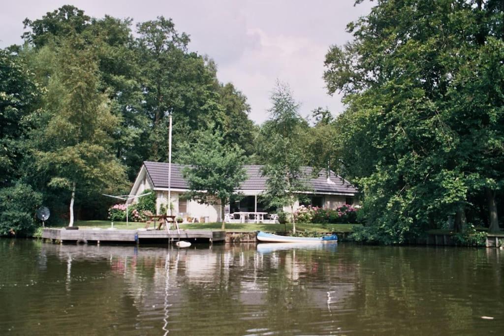 een huis op een dok met een boot op het water bij Comfortabele woning aan het water, hottub & kachel in Zuidlaren