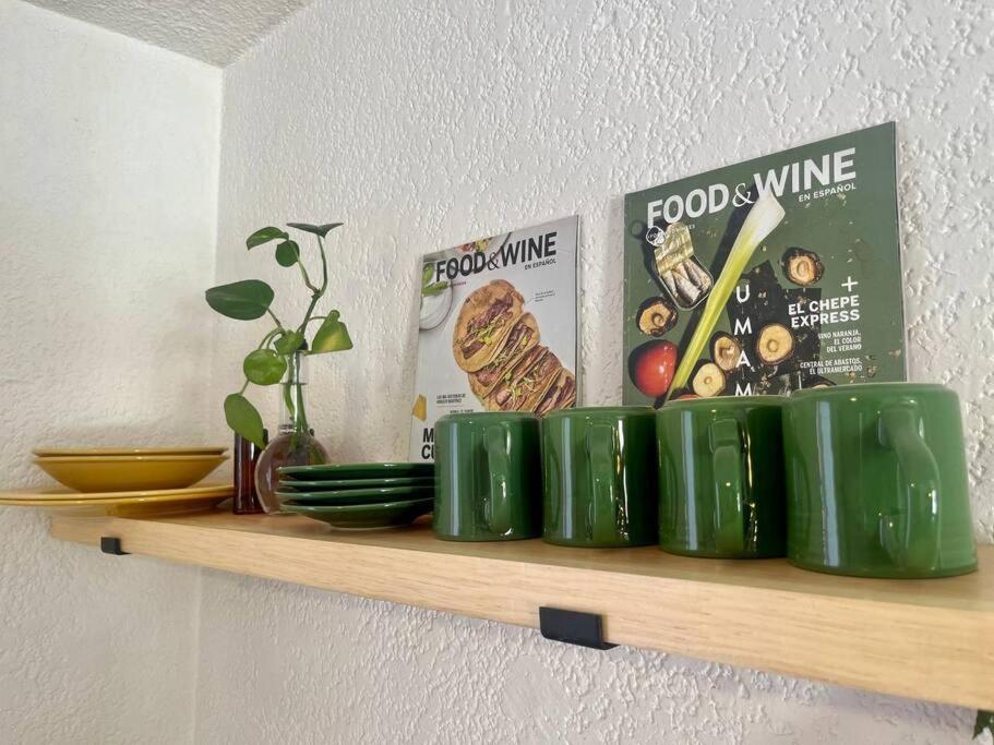 un estante con tazas verdes y libros en una pared en Depto. equipado, Dos Habitaciones, Zona Céntrica, en Tulancingo