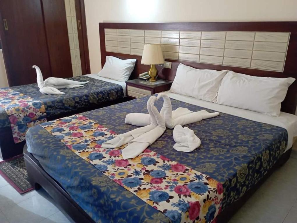 two beds with white shoes and towels on them at Windsor Hotel Luxor in Luxor