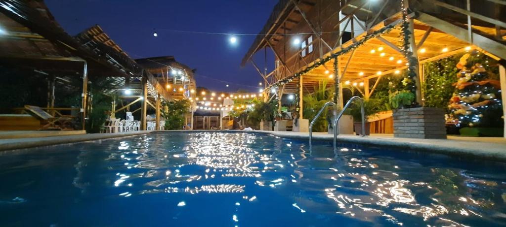 uma piscina à noite com luzes em Hostal El Cascol em Puerto López