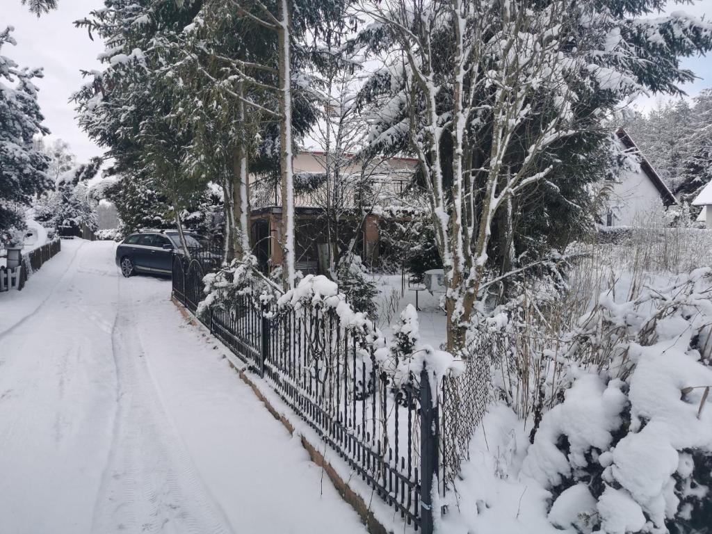 a fence covered in snow in front of a house at Willa widok na jezioro i las Swornegacie in Małe Swornigacie