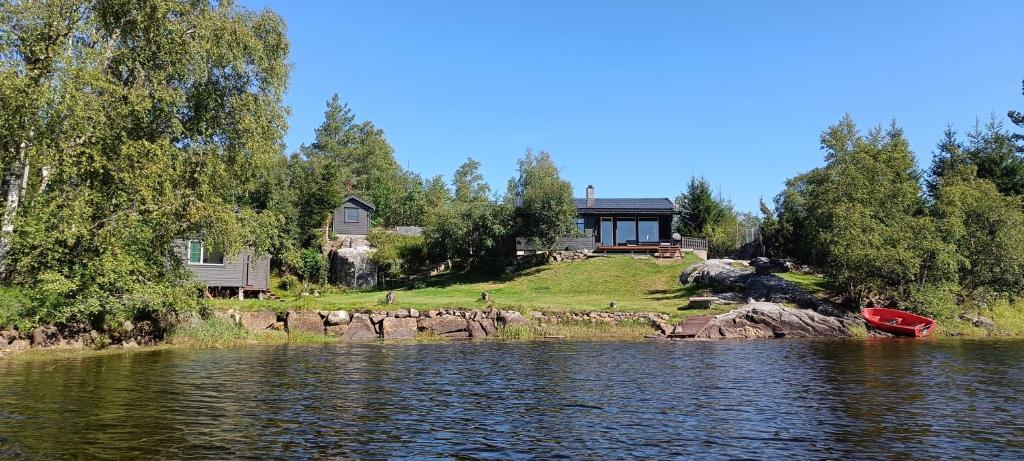 a house on the shore of a lake with a boat at Gauvik - Lyngdal in Lyngdal