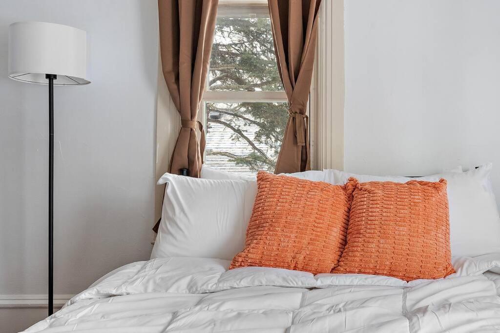 a bed with orange and white pillows in front of a window at 2 Bedroom/1 bath Upper Duplex in Hopkins