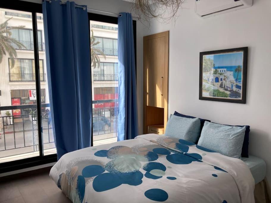 um quarto com uma cama com cortinas azuis e uma janela em Diamant de la marsa plage em La Marsa