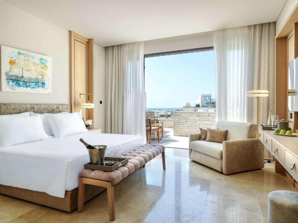a bedroom with a large white bed and a couch at Cap St Georges Hotel & Resort in Peyia