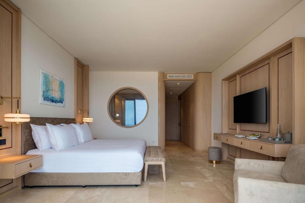 a hotel room with a bed and a tv at Cap St Georges Hotel & Resort in Peyia