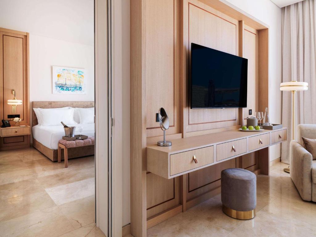 a hotel room with a television and a bedroom at Cap St Georges Hotel & Resort in Peyia