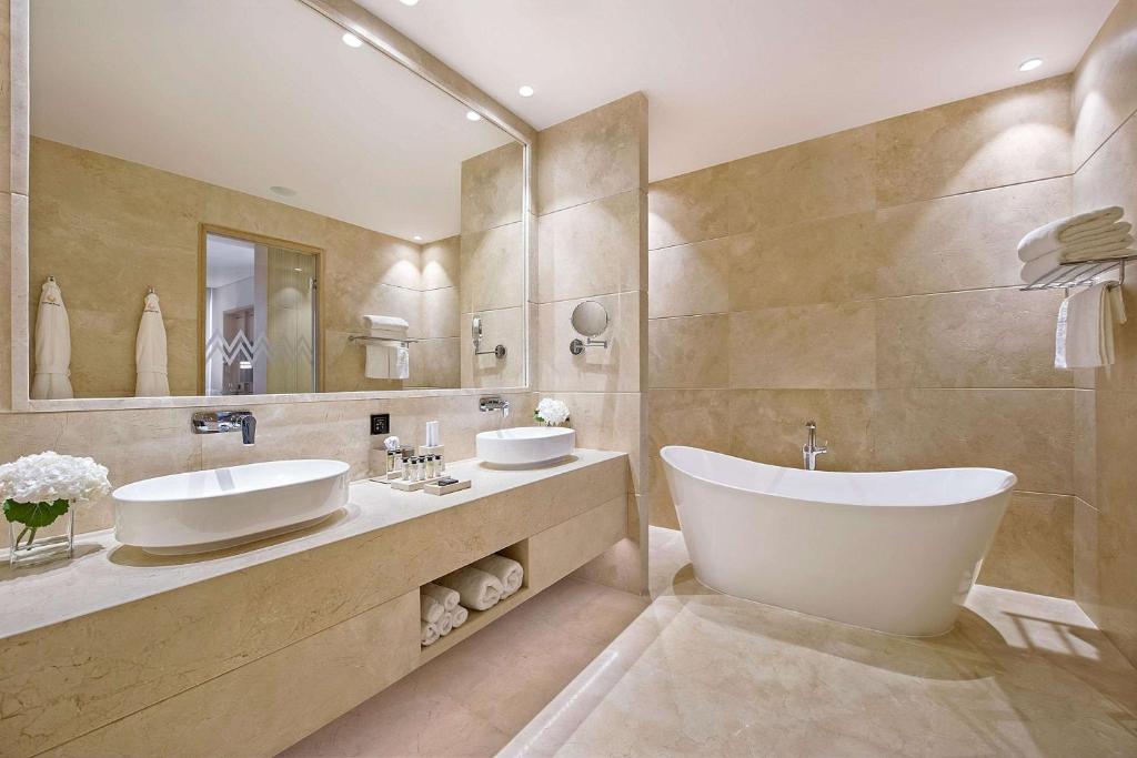 a bathroom with two sinks and a large mirror at Cap St Georges Hotel & Resort in Peyia