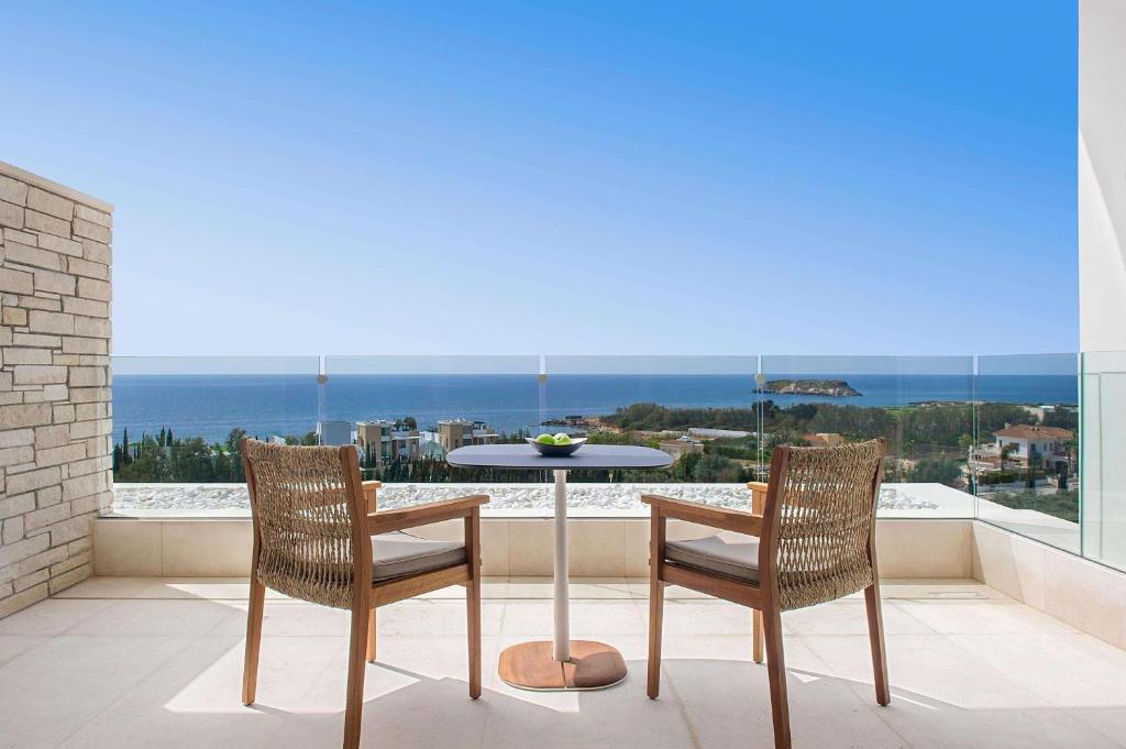 a table and chairs on a balcony with a view of the ocean at Cap St Georges Hotel & Resort in Peyia