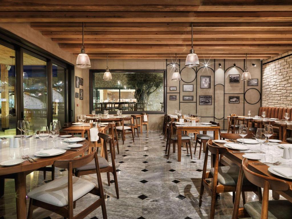a restaurant with wooden tables and chairs and windows at Cap St Georges Hotel & Resort in Peyia