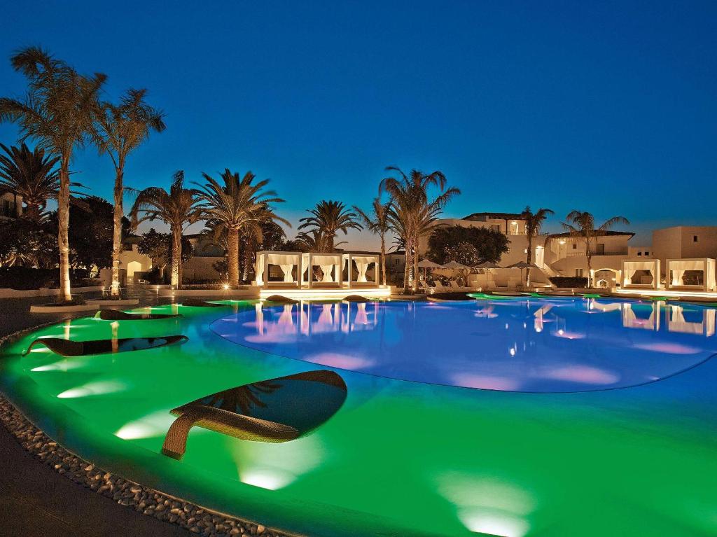 uma grande piscina à noite com iluminação verde em Caramel Grecotel Boutique Resort em Adelianos Kampos