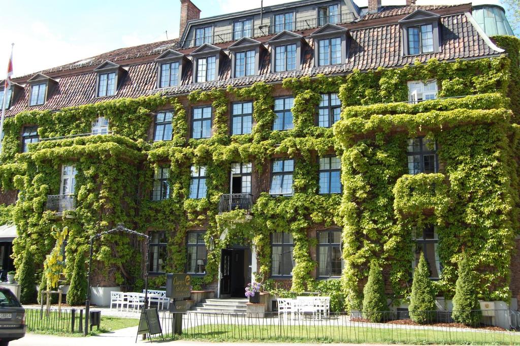 a building covered in ivy on a street at Clarion Collection Hotel Gabelshus in Oslo