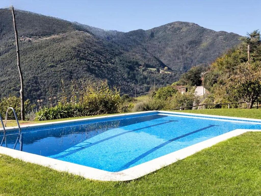 uma piscina na relva com montanhas ao fundo em House with garden, games area and shared pool em Montseny