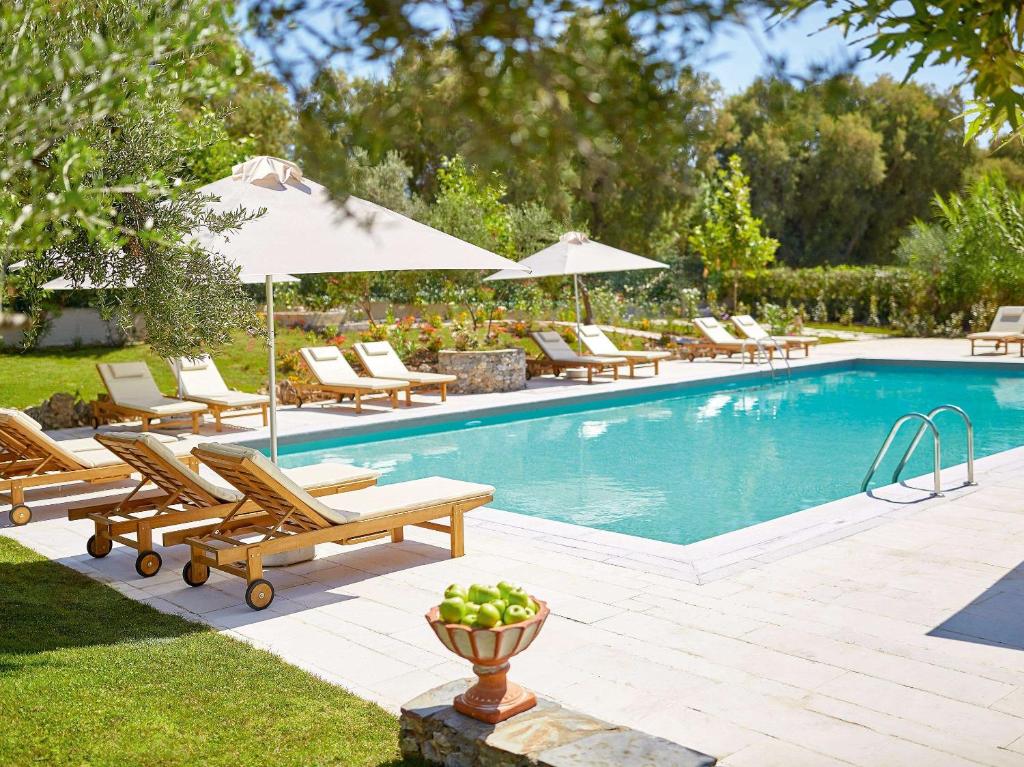 a swimming pool with chairs and umbrellas next to at Villa Oliva in Adelianos Kampos