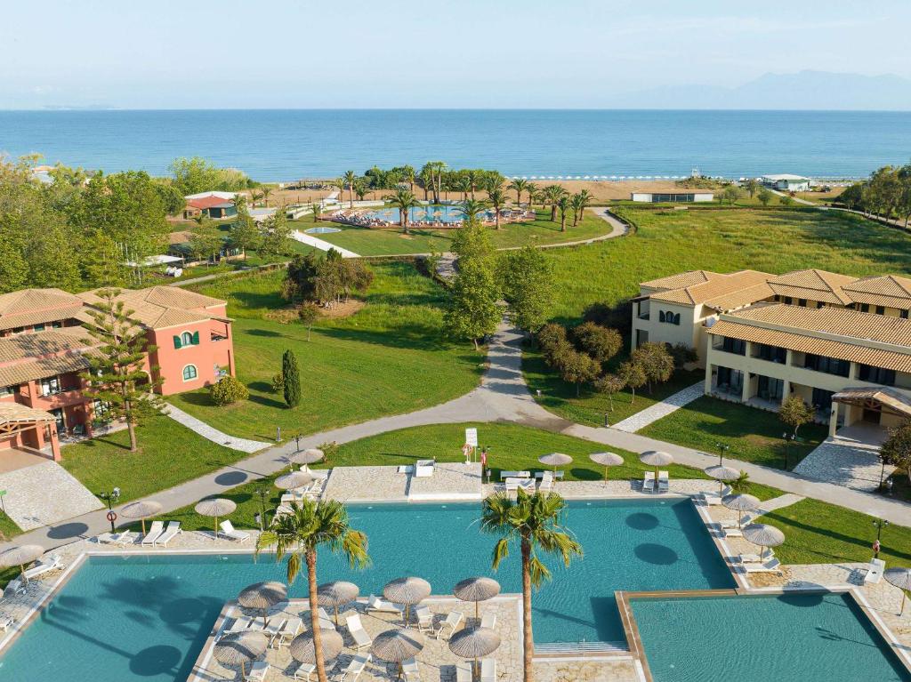 an aerial view of a resort with a pool and the ocean at Grecotel LUXME Costa Botanica in Acharavi