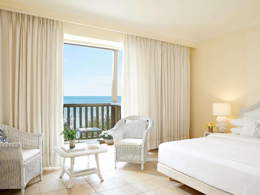 a bedroom with a bed and a balcony with the ocean at Grecotel Marine Palace & Aqua Park in Panormos Rethymno