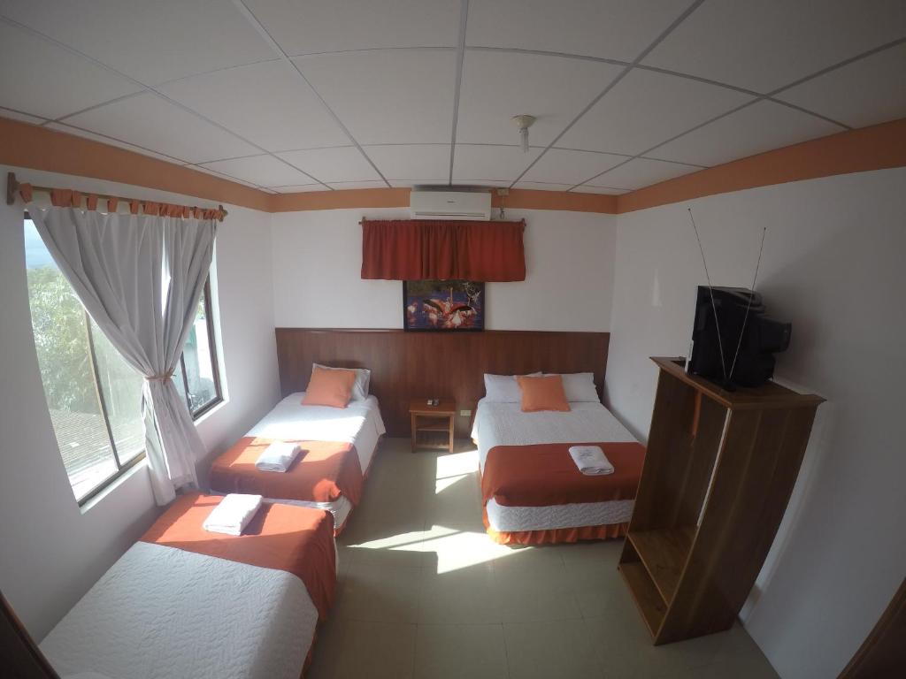 a room with three beds and a television in it at CASA HOSPEDAJE SEA LIONS in Puerto Villamil