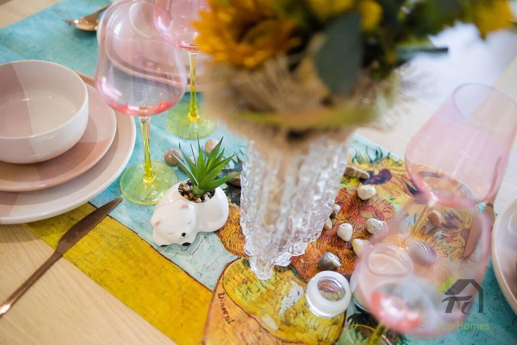 Una mesa con un jarrón con flores y copas de vino. en Van Gogh's Condo in Parramatta, en Sídney