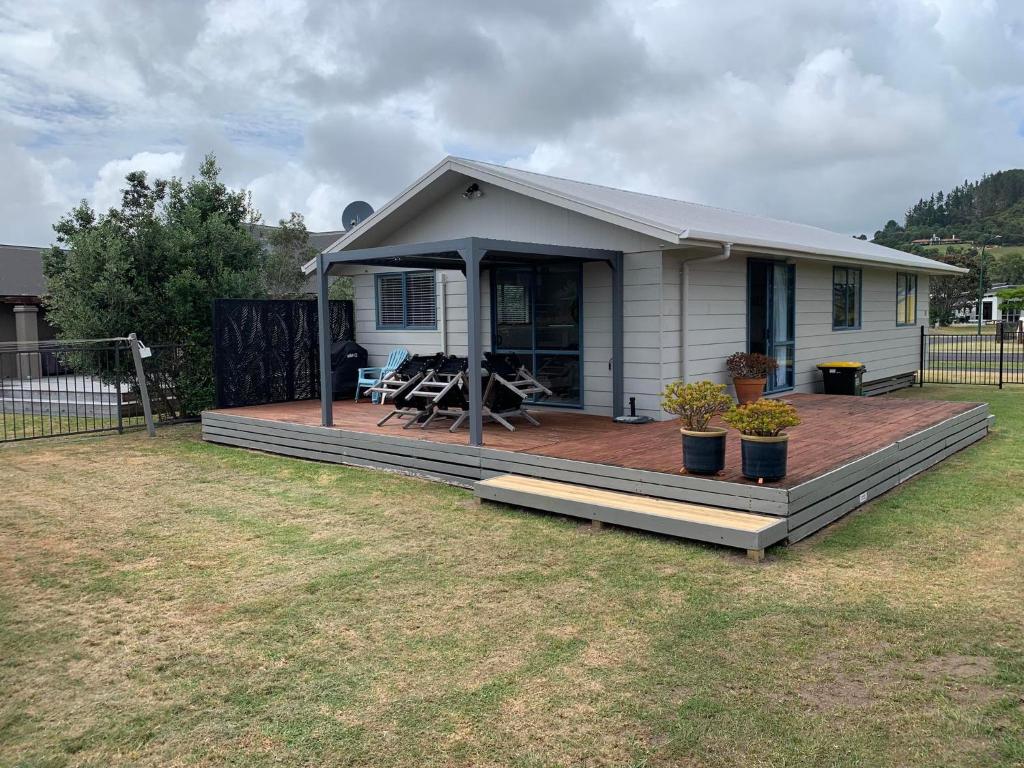 a small house with a deck in a yard at Charming on Charles in Cooks Beach