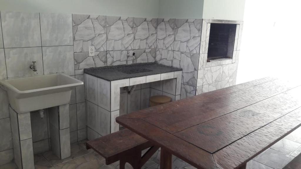 ein Badezimmer mit einem Waschbecken, einer Theke und einem Tisch in der Unterkunft Casa verde in Pontal do Paraná