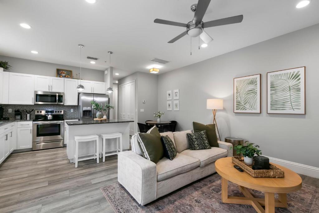 een woonkamer en een keuken met een bank en een tafel bij NEW! Canopy Cove, Luxury Downtown Apartment Near Main St in Safety Harbor