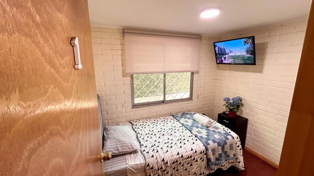 Dormitorio pequeño con cama y TV en Chez Humbert en Santiago