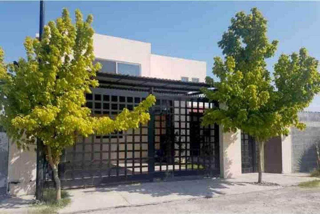 a building with a gate in front of two trees at Casa cerca de parque industrial in Monclova