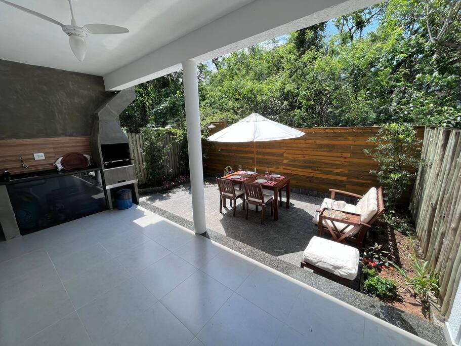 um pátio com uma mesa, cadeiras e um guarda-sol em Casa completa cond. fechado em Paúba, S. Sebastião em São Sebastião